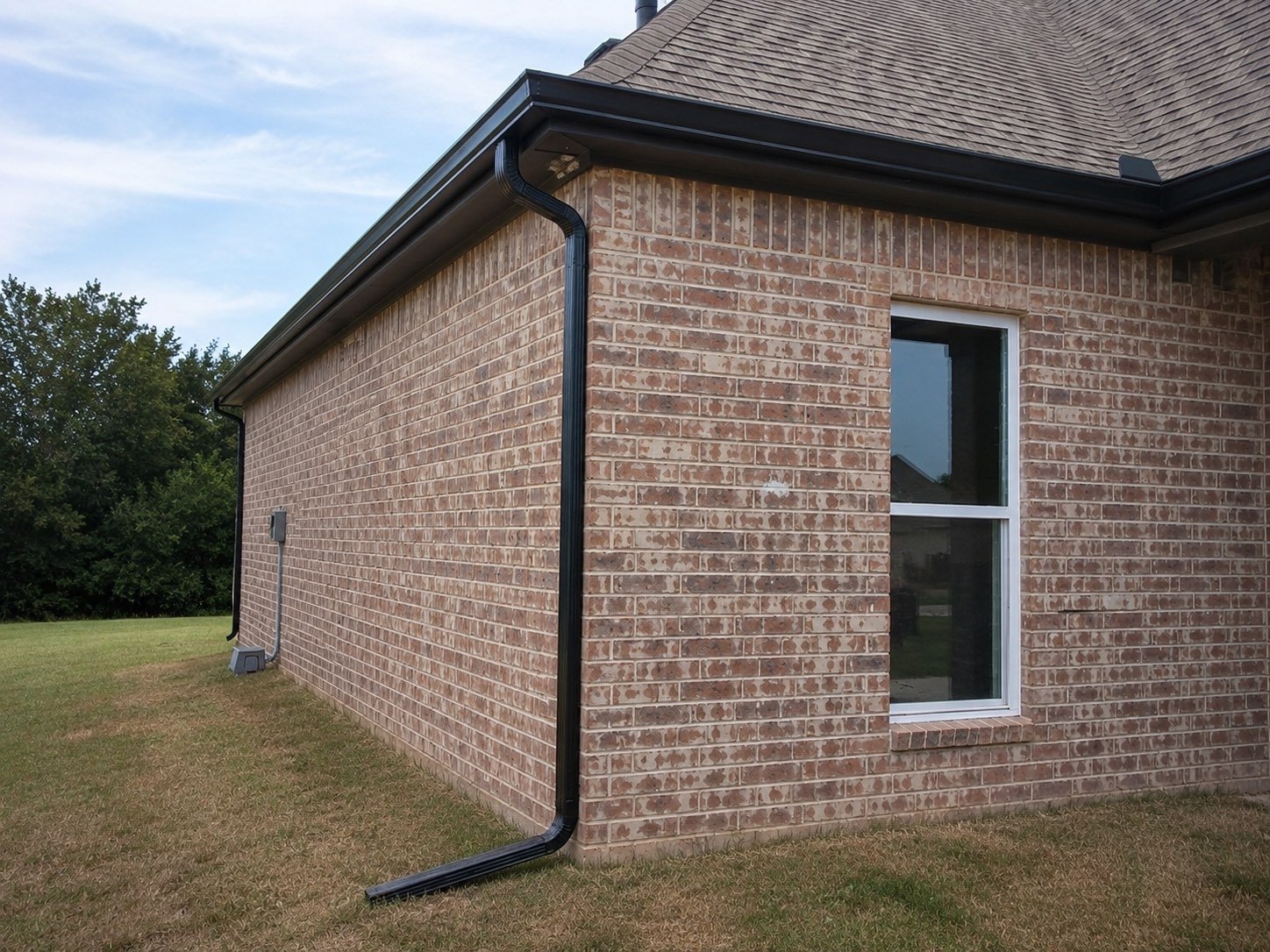 Black seamless gutters and downspout running the full length of a brick home in Edinburg, Texas