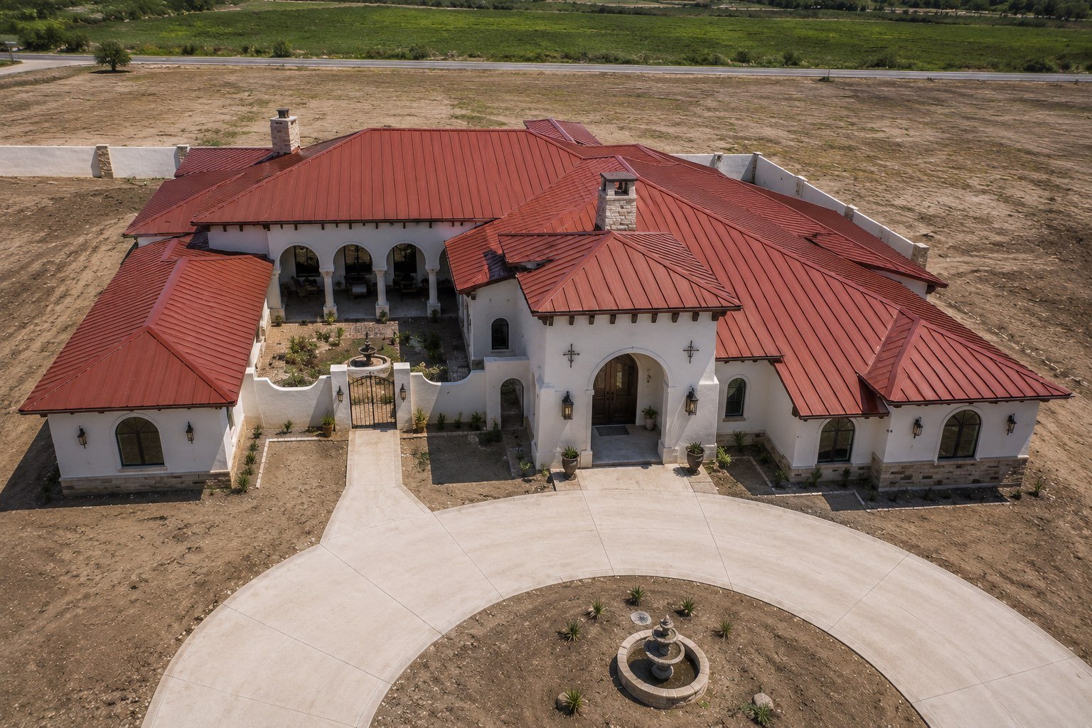 Terracotta red standing seam metal roof on a large Spanish-style estate in the Rio Grande Valley